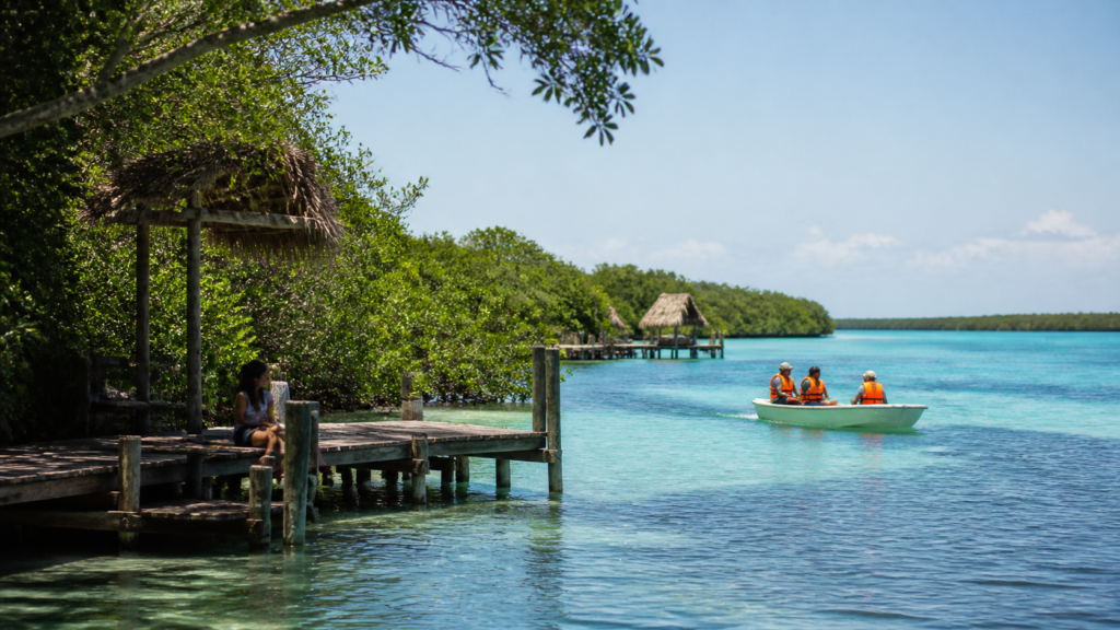 Lancha pequeña con chalecos salvavidas sobre la laguna de Bacalar, rodeada de manglar y agua azul clara.