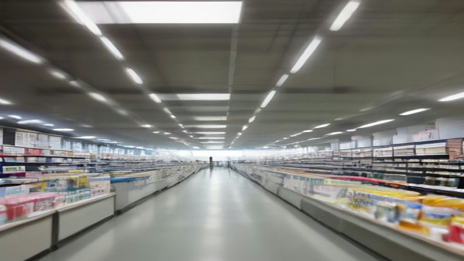 Pasillo largo de una tienda departamental con anaqueles llenos de productos bajo luces blancas