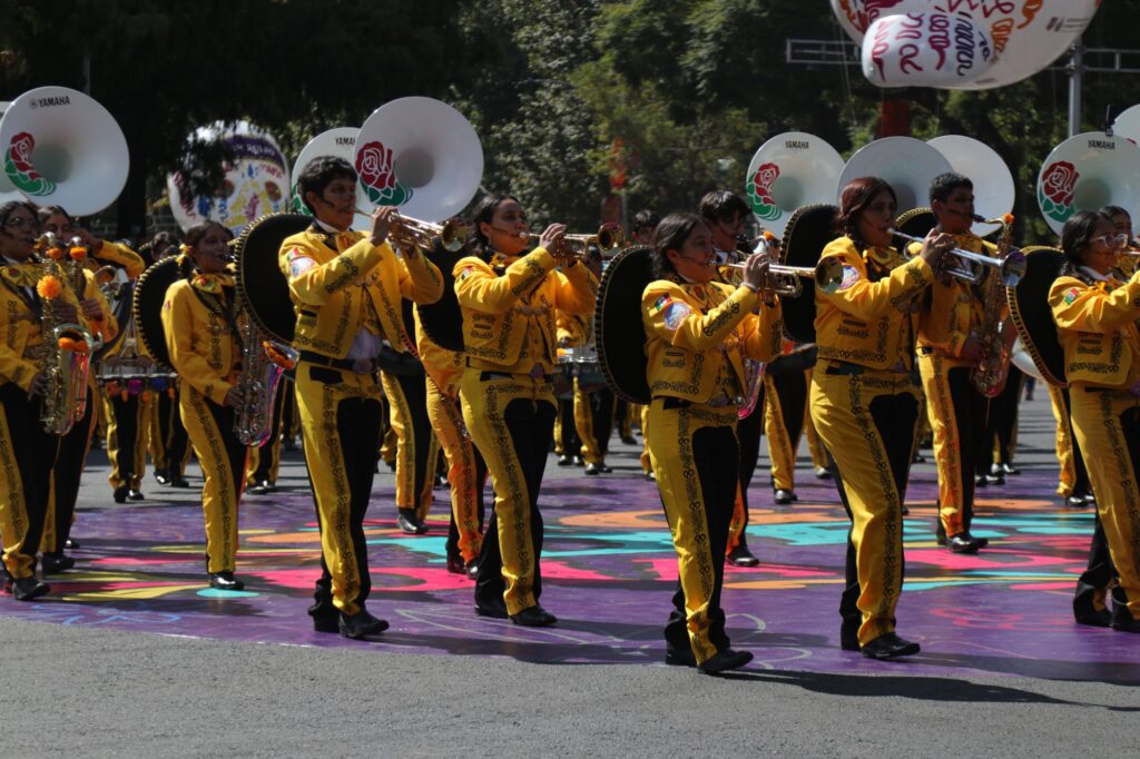 Banda de marcha con trajes de charro amarillos avanza por Paseo de la Reforma en el Gran Desfile de Día de Muertos 2026